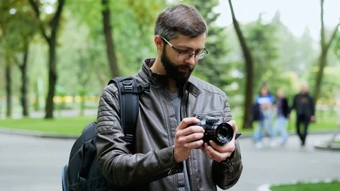 Happy bearded man with camera takes a photo in the park Stock Footage 107949470