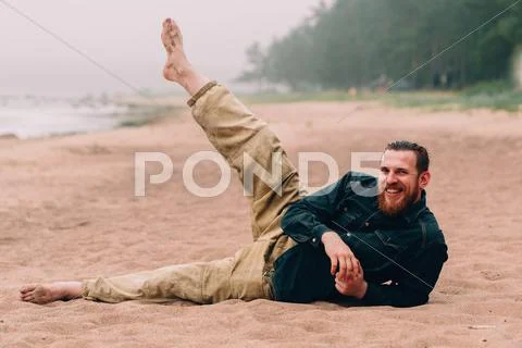Happy bearded man does morning exercises at the beach Stock Photos