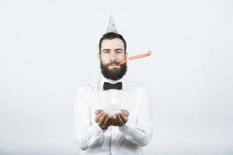Happy bearded man in party or birthday caps blows a horn and holds a gift in  Stock Photos