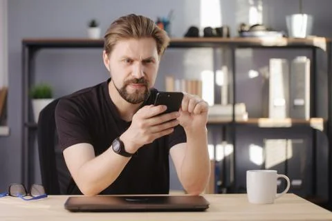 Happy bearded man using smartphone while sitting at home Stock-Fotos