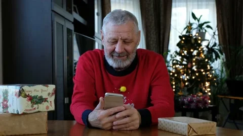 Happy beared senior man in red christmas sweater talking on the smart phone, vid Stock Footage 144873651