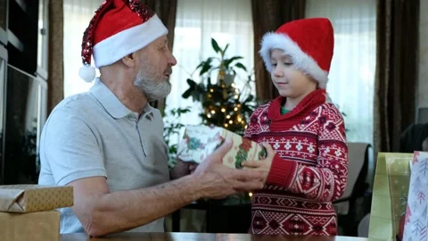 Happy beared senior man in red christmas hat with his grandson and gifts Stock Footage 144969932