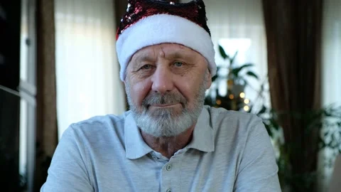 Happy beared senior man in red christmas hat looking at camera, close up Stock Footage 145124754