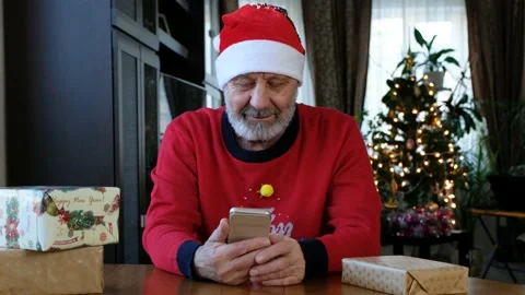 Happy beared senior man in red christmas sweater talking on the smart phone Stock Footage 145124992