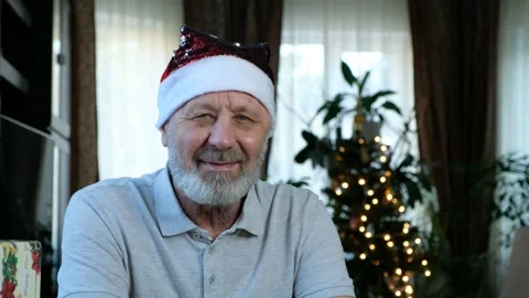 Happy beared senior man in red christmas hat looking at camera, close up Stock Footage 145191948