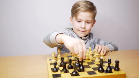 Happy beautiful boy playing chess. Caucasian child concentrates while playing Stock Footage 123202082