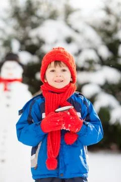 Happy beautiful child building snowman in garden, winter time Stock Photos