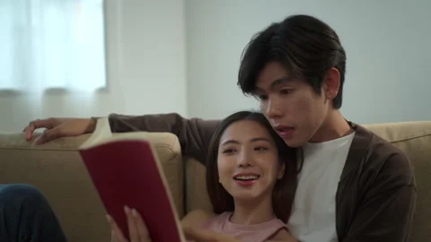 Happy beautiful couple embracing while reading a book together with romance rela Stock Footage 283830517