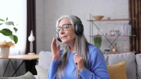 Happy beautiful elderly gray-haired woman in black headphones enjoy listening Video stock 213278081