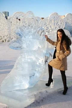 Happy beautiful girl stands near big ice shoe at sunny winter day. Stock Photos
