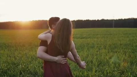 Happy beautiful lovers have fun in nature. Man and woman dance in a field at Stock Footage 69768342