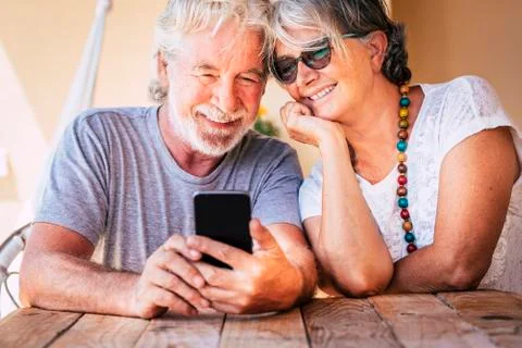 Happy beautiful senior old couple do a phone call with modern online technolo Stock Photos