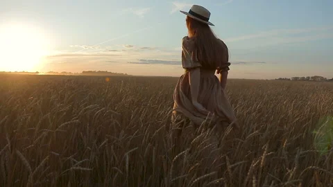 Happy beautiful woman in good mood walks through yellow wheat field and rejoices Stock Footage