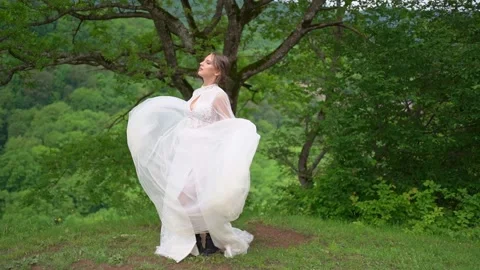 Happy beautiful young woman in a wedding dress in the woods in the mountains Stock Footage