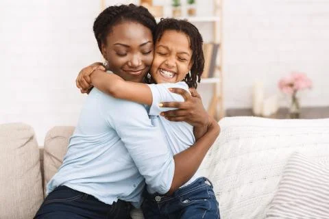 Happy black family hugging and embracing on couch Stock Photos