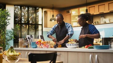 Happy black man squeezing lemon juice over fresh vegetables Fotos Stock