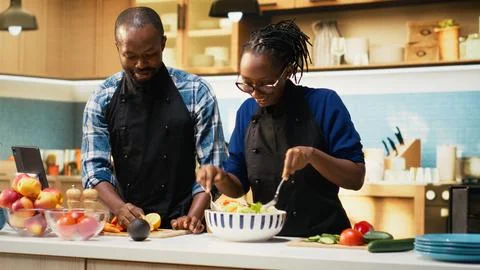 Happy black man squeezing lemon juice over fresh vegetables Fotos Stock