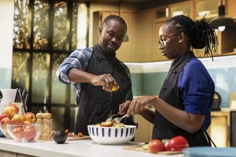 Happy black man squeezing lemon juice over fresh vegetables Fotos Stock