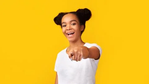 Happy black teenager choosing you over yellow background Stock Photos
