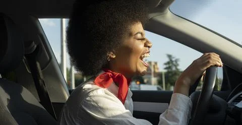 Happy black woman driving car and smiling brightly Stock Photos