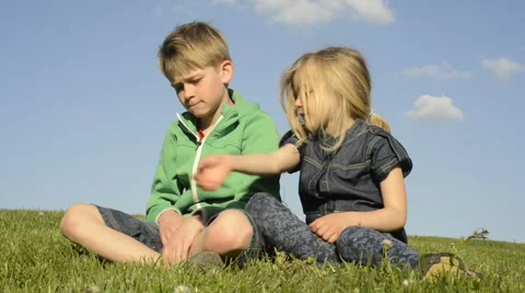 Happy blond children using smartphone sitting on the grass. Brother and sister. Vidéo 63038731