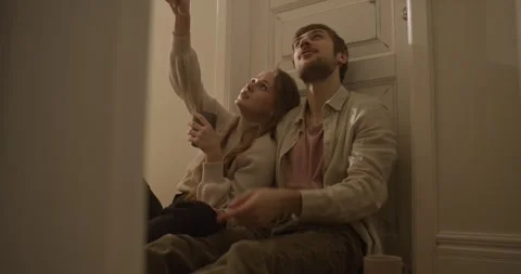 A happy blond guy with stubble and his girlfriend are sitting on the floor and 스톡 동영상 309468939