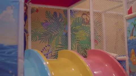 Happy blond toddler slides down into dry pool with balls Stock Footage 84660704