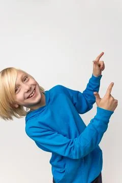 Happy blonde boy smiling at camera, indicating direction and presenting a c.. Fotos Stock