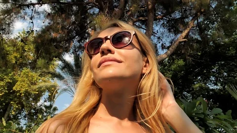 Happy blonde girl revolves around herself examining a beautiful tropical park. Stock Footage 129200322