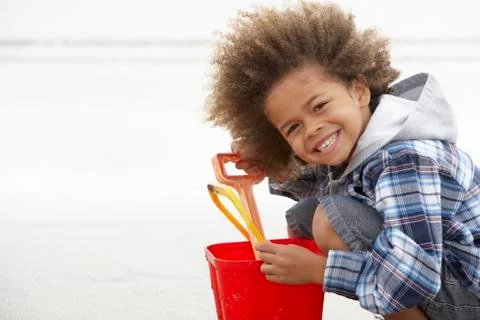 Happy boy at beach with bucket and spade Stock Photos