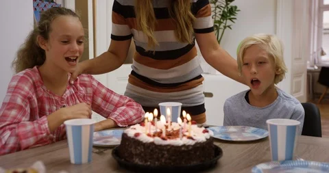 Happy Boy Blowing Out Candles While Celebrating With Family Stock Footage 124901799