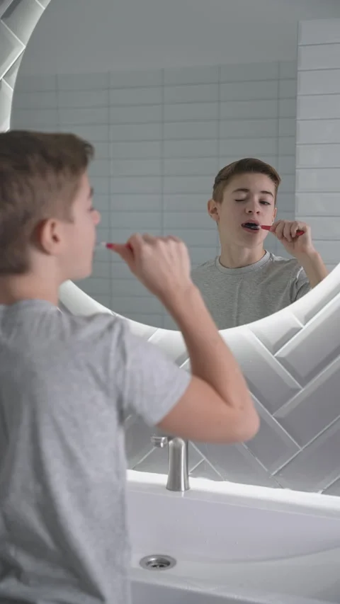 Happy boy cleaning teeth in white bathroom looking to mirror.  Stock Footage 273074101