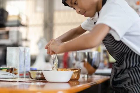 Happy boy cracking an egg for baking a cake in kitchen. 스톡 일러스트