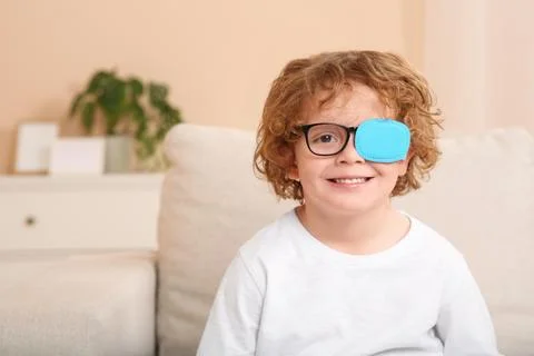 Happy boy with eye patch on glasses indoors, space for text. Strabismus tre.. Stock Photos