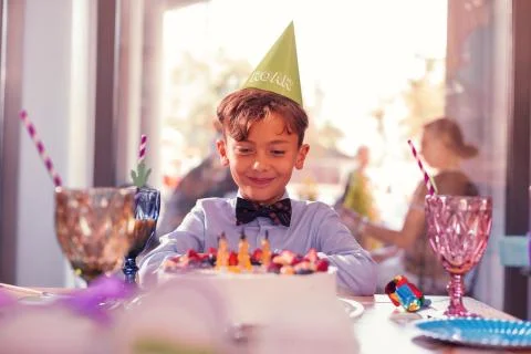 Happy boy feeling satisfied while looking at his birthday cake Stock Photos