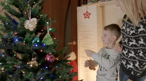 Happy boy hanging gingerbread on christmas tree with mother Stock Footage