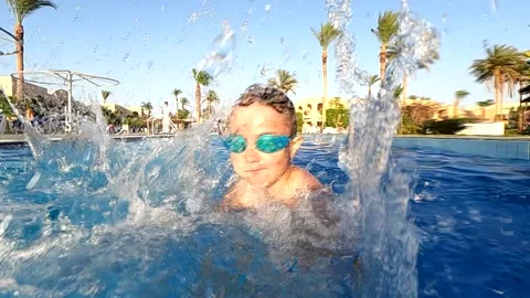 Happy boy having fun in the pool, creates splashes in the pool wearing safety Stock Footage 236278835