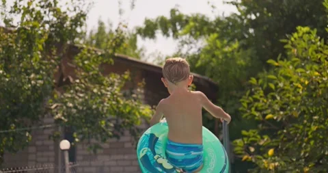 Happy boy with inflatable ring jumps in the pool, enjoys swimming in the pool Stock Footage 260336504