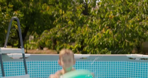 Happy boy with inflatable ring jumps in the pool, enjoys swimming in the pool Stock Footage 260486195