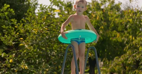 Happy boy with inflatable ring jumps in the pool, enjoys swimming in the pool Stock Footage 260845328