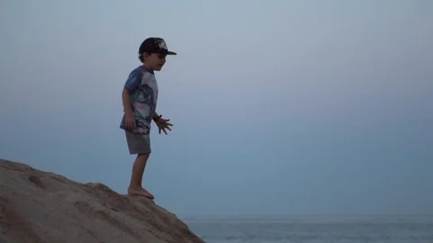 Happy boy jumping down into soft white sand Stock Footage 113459223