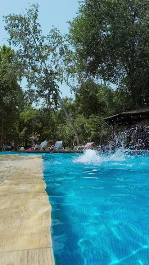 Happy boy jumping in a pool splashing water relaxing on a sunny summer day Stock Footage 313234764