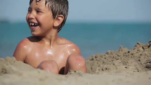 Happy boy jumping into sand pit on seashore Stock Footage 293494092
