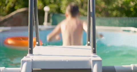 Happy boy jumping into swimming pool, child having fun, splashing water Stock Footage 259508562