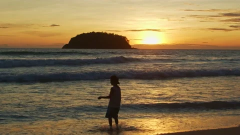A happy boy jumping on the waves at golden sunset Stock Footage 159381659