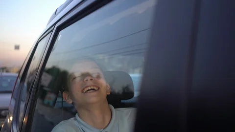 Happy boy laughs sitting in the back seat of the car Видео 110844802