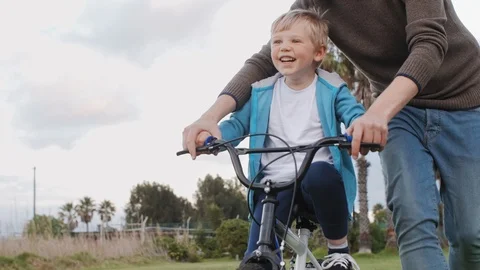 Happy boy learning to ride a bicycle with dad Stock Footage 120355239