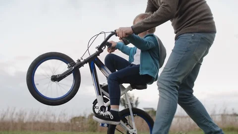 Happy boy learning to ride a bicycle with dad Stock Footage 120357452