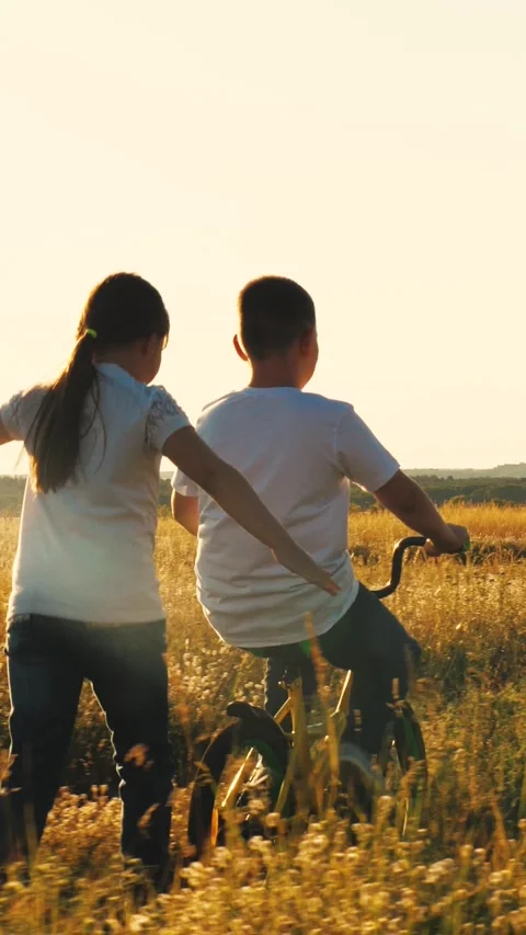 Happy boy learning ride bicycle park, child schoolboy son rides bicycle sunset Stock Footage 270796166