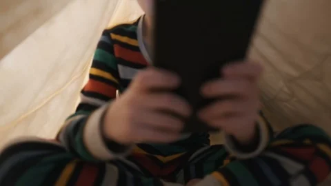 A happy boy is lying in bed under a yellow blanket playing the game tablet Stock Footage 105268749